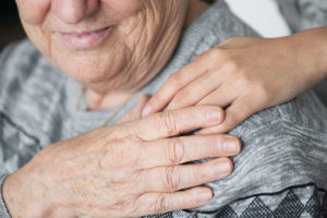 The hand of a trustee on their family members shoulder for a qualfied income trust for elder care