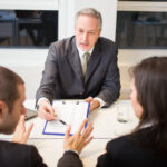 A family law lawyer talks with a couple while reviewing paperwork in Ball Ground, GA.